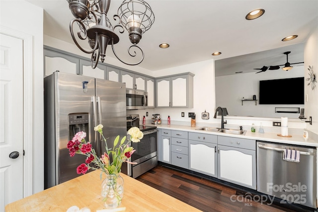 kitchen with sink, gray cabinetry, an inviting chandelier, stainless steel appliances, and dark hardwood / wood-style floors