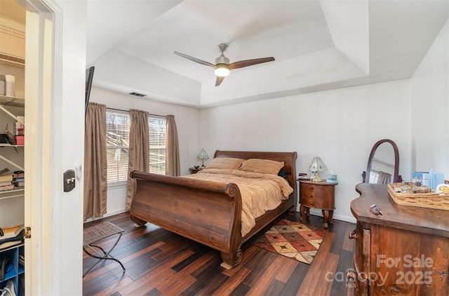 bedroom featuring dark wood-type flooring, ceiling fan, and a raised ceiling