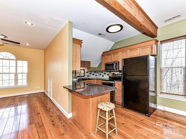 kitchen with a kitchen breakfast bar, decorative backsplash, kitchen peninsula, stainless steel appliances, and a healthy amount of sunlight