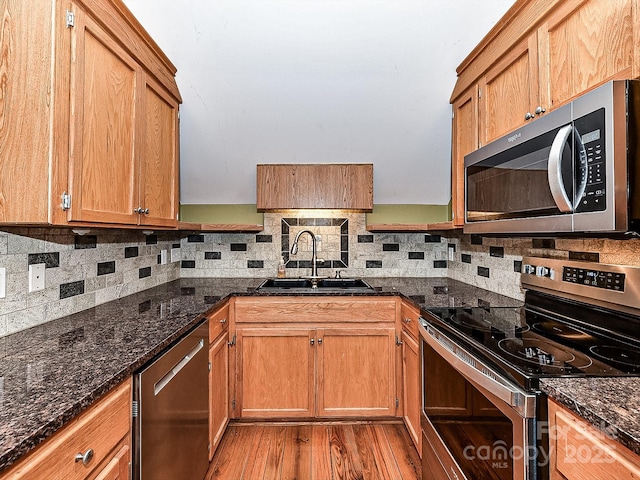 kitchen with dark stone countertops, sink, tasteful backsplash, and appliances with stainless steel finishes