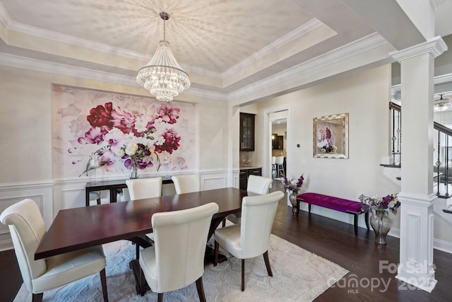 dining area featuring decorative columns, a notable chandelier, ornamental molding, dark hardwood / wood-style flooring, and a raised ceiling