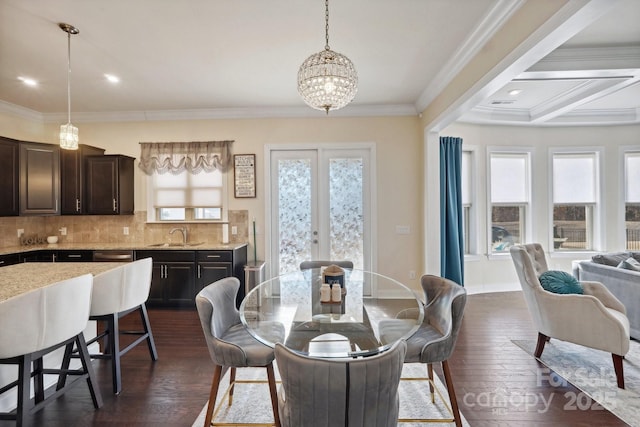 dining space featuring sink, dark wood-type flooring, an inviting chandelier, ornamental molding, and french doors