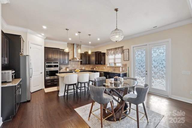 dining space featuring dark wood-type flooring, crown molding, and sink