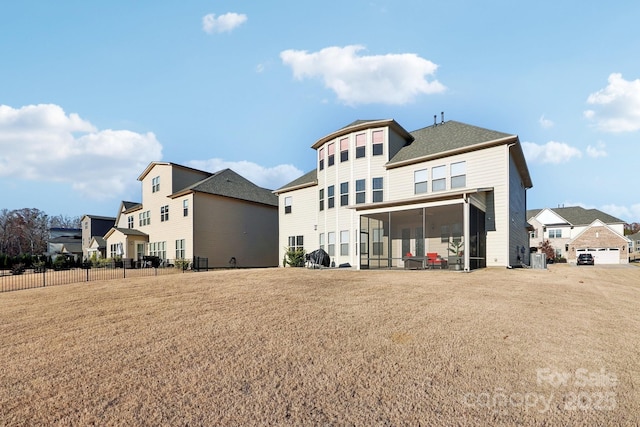 rear view of property with a sunroom and a lawn