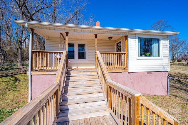 exterior space featuring a chimney, a porch, crawl space, fence, and a front lawn