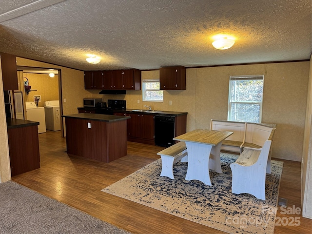 kitchen with sink, light hardwood / wood-style flooring, dishwasher, a kitchen island, and independent washer and dryer