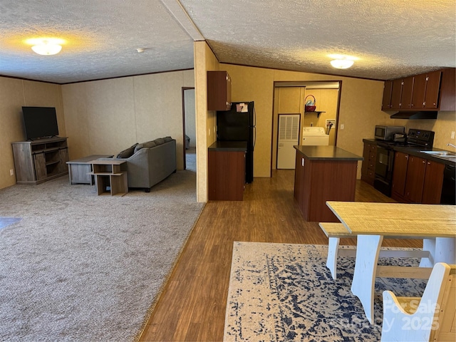 kitchen featuring sink, a center island, dark hardwood / wood-style flooring, washer / clothes dryer, and black appliances