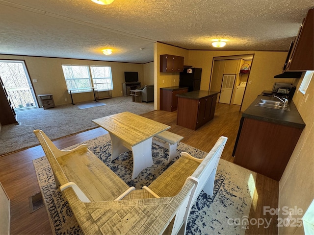 dining space featuring dark hardwood / wood-style flooring, sink, and a textured ceiling