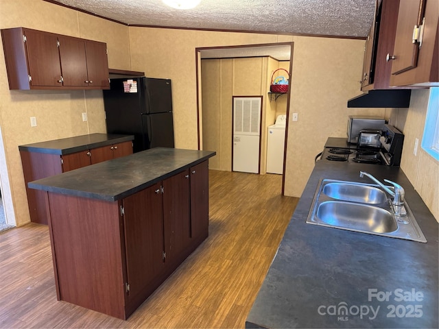 kitchen featuring sink, stove, light hardwood / wood-style floors, a textured ceiling, and black fridge