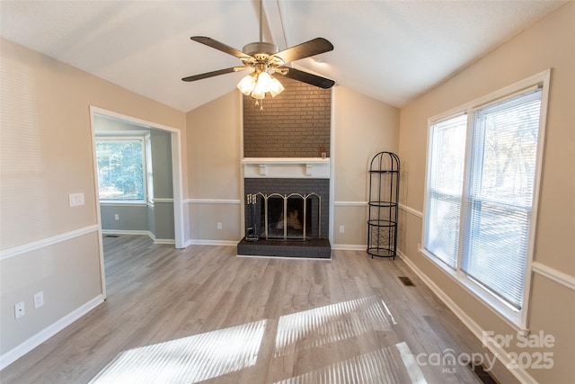 unfurnished living room with vaulted ceiling, light wood-type flooring, ceiling fan, and a fireplace