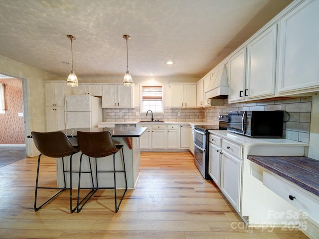 kitchen featuring white cabinetry, double oven range, white refrigerator, custom range hood, and a kitchen island