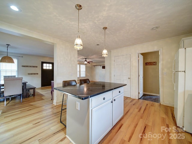 kitchen with pendant lighting, a kitchen breakfast bar, white fridge, and white cabinets