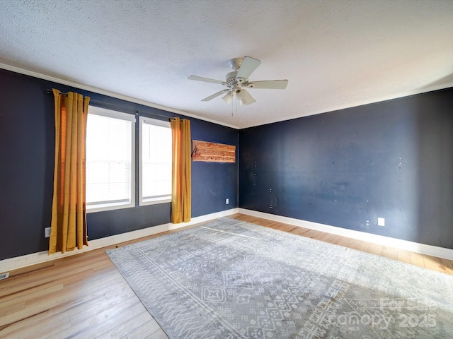 empty room with ceiling fan, ornamental molding, a textured ceiling, and light wood-type flooring