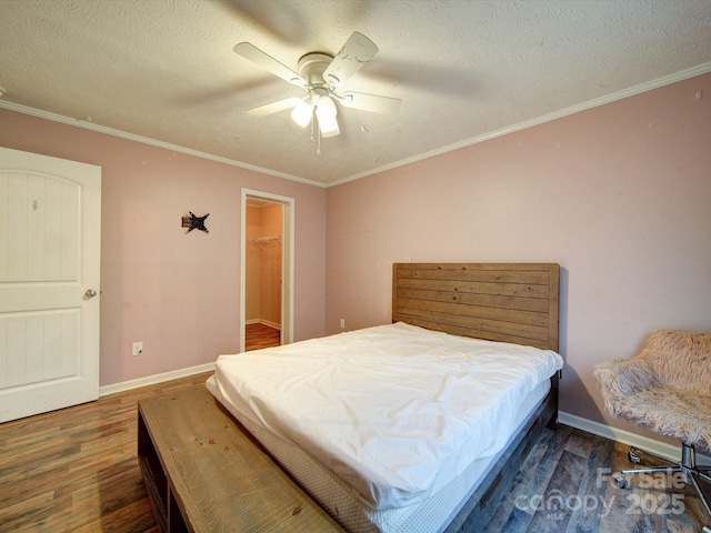 bedroom with crown molding, a walk in closet, dark hardwood / wood-style floors, and a textured ceiling