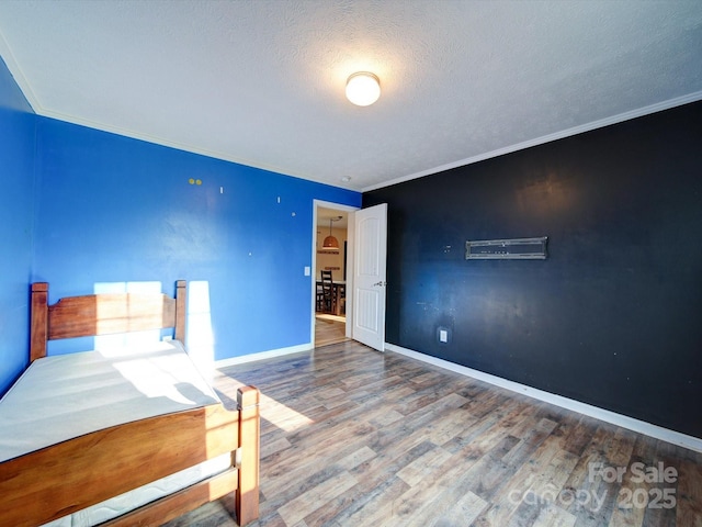 unfurnished bedroom featuring hardwood / wood-style floors, ornamental molding, and a textured ceiling