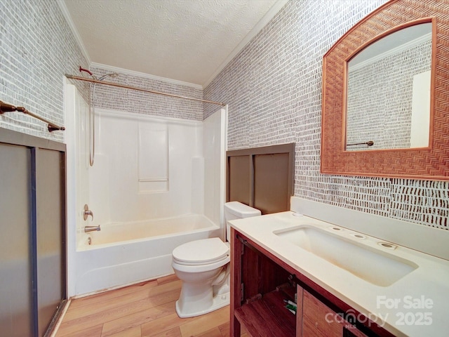 full bathroom featuring crown molding, vanity, wood-type flooring, a textured ceiling, and bathtub / shower combination