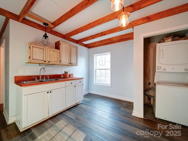 kitchen with stacked washer and clothes dryer, sink, pendant lighting, and dark wood-type flooring