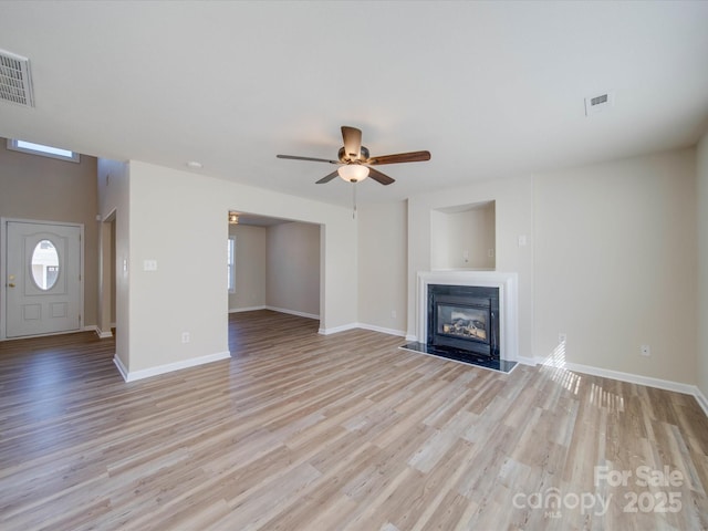 unfurnished living room with visible vents, a glass covered fireplace, and light wood-style flooring