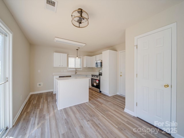 kitchen featuring visible vents, light countertops, appliances with stainless steel finishes, white cabinets, and a sink