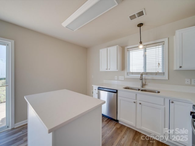 kitchen featuring stainless steel dishwasher, white cabinets, visible vents, and a sink