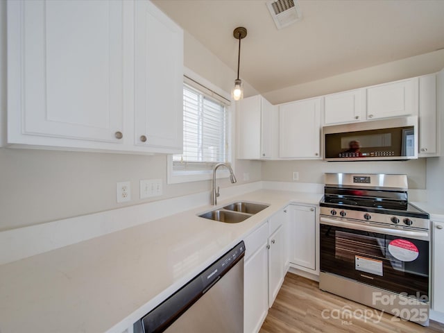 kitchen with a sink, visible vents, white cabinetry, and stainless steel appliances