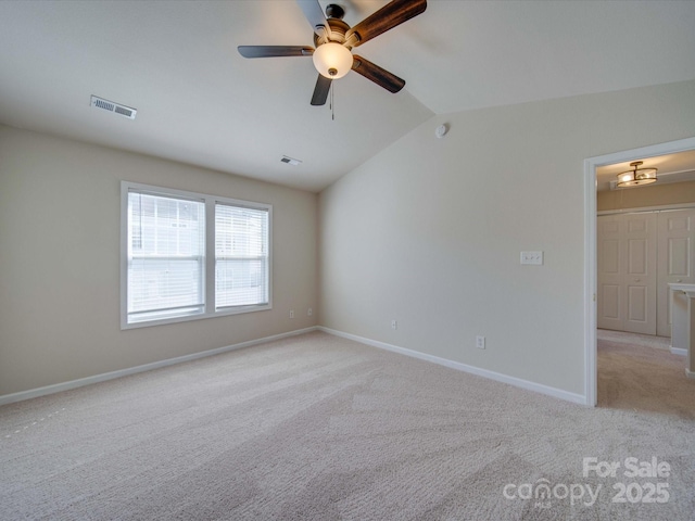 spare room featuring vaulted ceiling, baseboards, visible vents, and light carpet