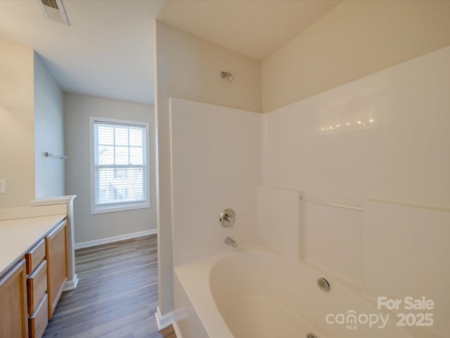 full bath featuring vanity, wood finished floors, visible vents, baseboards, and bathtub / shower combination