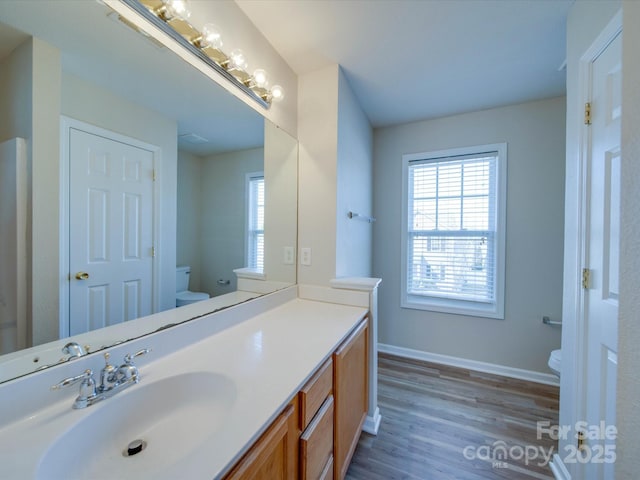 bathroom with plenty of natural light, toilet, vanity, and baseboards