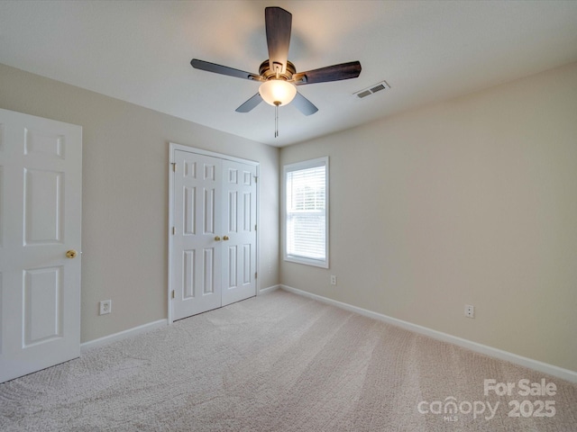 unfurnished bedroom featuring visible vents, baseboards, ceiling fan, light colored carpet, and a closet