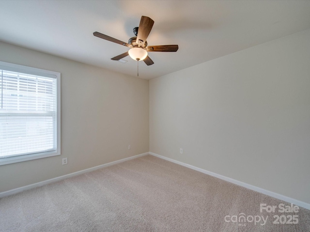 carpeted empty room with a ceiling fan and baseboards