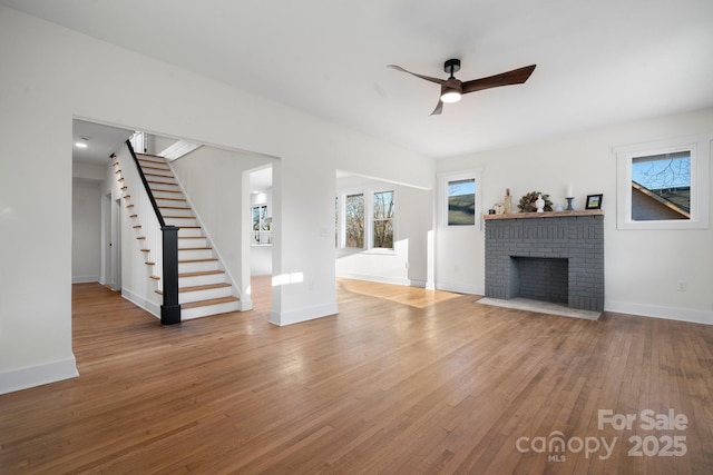 unfurnished living room featuring ceiling fan, a fireplace, and wood-type flooring