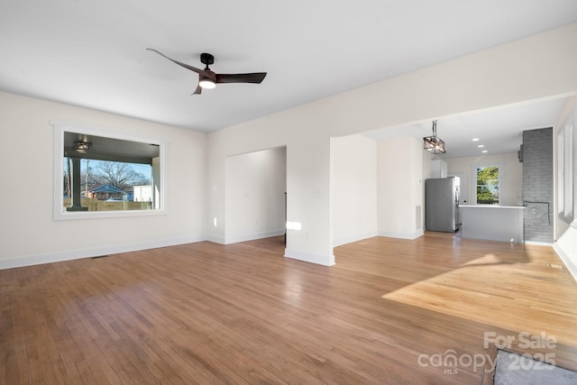 unfurnished living room with ceiling fan, a fireplace, and light wood-type flooring