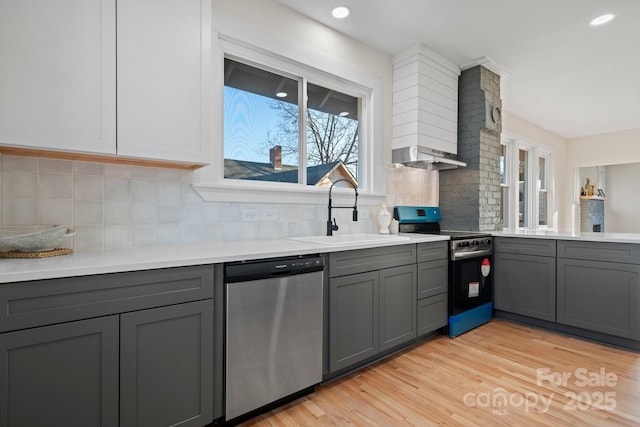 kitchen featuring sink, light wood-type flooring, appliances with stainless steel finishes, gray cabinets, and backsplash