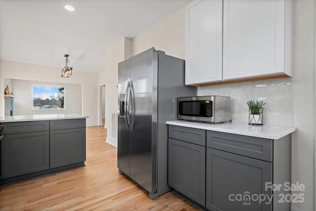 kitchen with gray cabinets, stainless steel appliances, tasteful backsplash, white cabinets, and decorative light fixtures