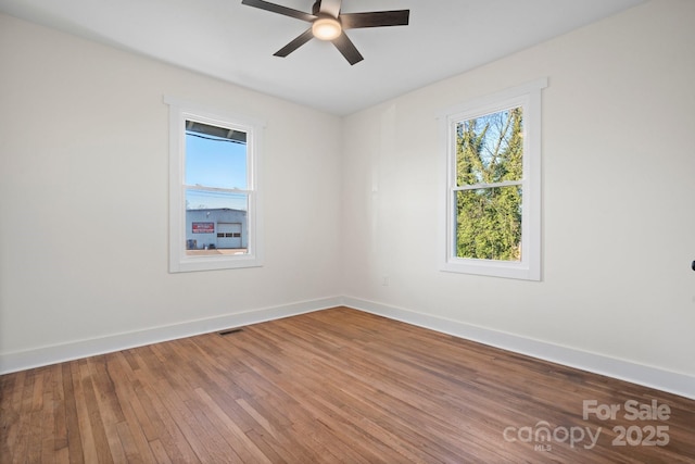 spare room with wood-type flooring, a healthy amount of sunlight, and ceiling fan