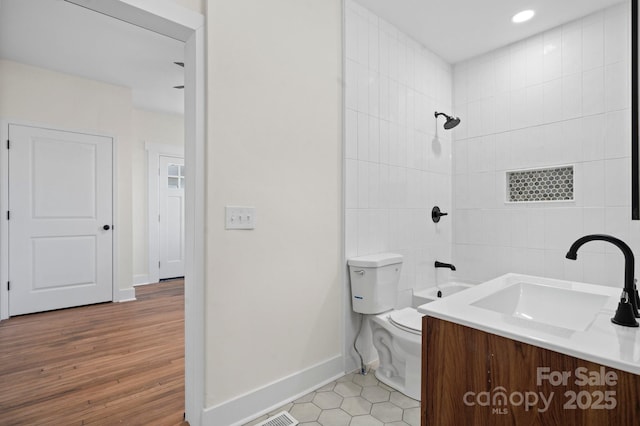 full bathroom featuring tiled shower / bath, vanity, toilet, and hardwood / wood-style floors