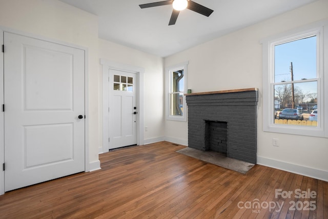 unfurnished living room featuring a brick fireplace, dark wood-type flooring, and ceiling fan