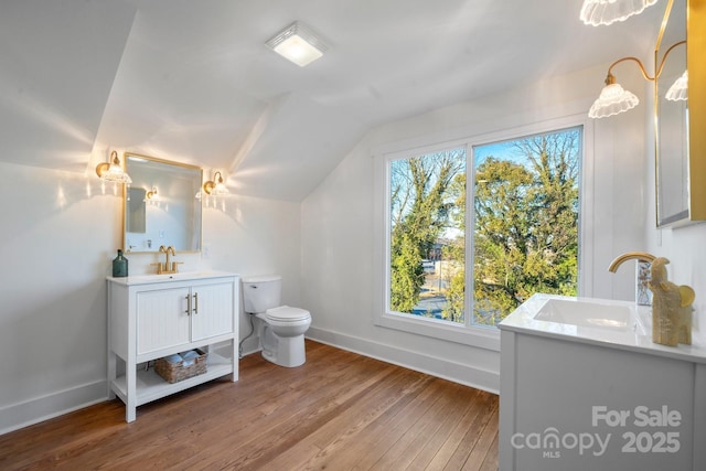 bathroom featuring hardwood / wood-style flooring, lofted ceiling, toilet, and vanity