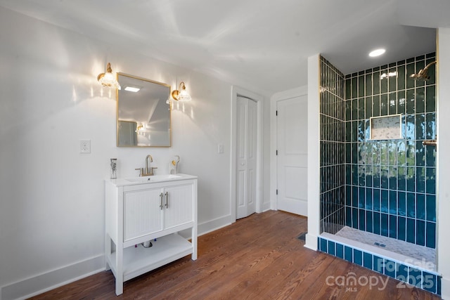 bathroom with vanity, hardwood / wood-style flooring, and a tile shower