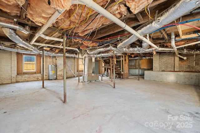 basement with brick wall, electric water heater, and heating unit