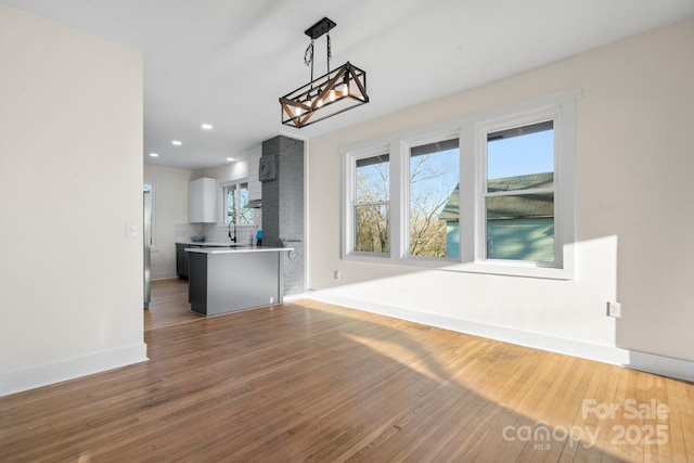 unfurnished dining area featuring light wood-style floors, baseboards, a chandelier, and recessed lighting