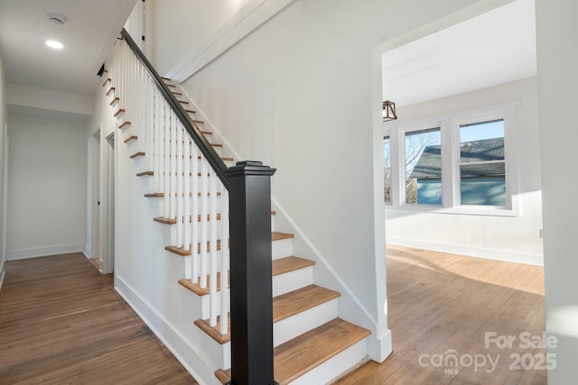 stairs featuring wood finished floors, baseboards, and recessed lighting