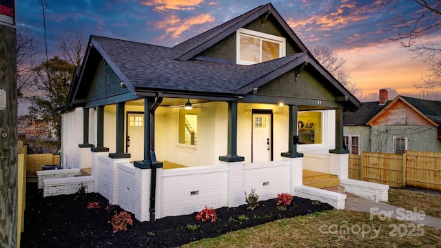 rear view of property with a porch, a shingled roof, and a fenced front yard