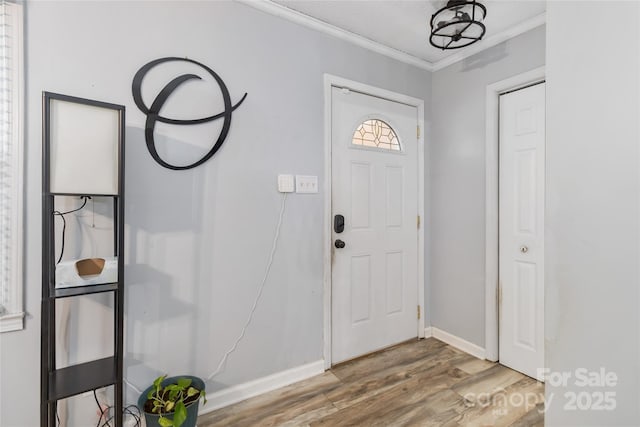 foyer entrance featuring baseboards, crown molding, and wood finished floors