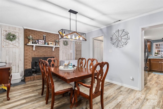 dining room featuring light wood-style flooring, baseboards, ornamental molding, and visible vents