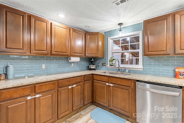 kitchen featuring a sink, visible vents, light stone counters, brown cabinets, and dishwasher