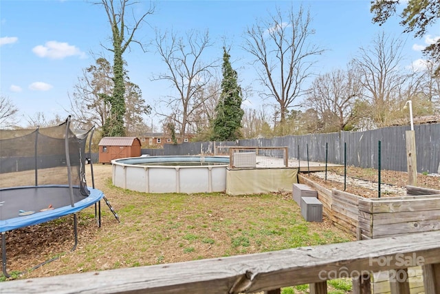 view of yard with a shed, a trampoline, a fenced in pool, and a fenced backyard