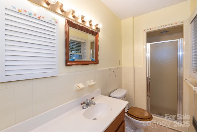 bathroom featuring a wainscoted wall, tile walls, toilet, a stall shower, and vanity