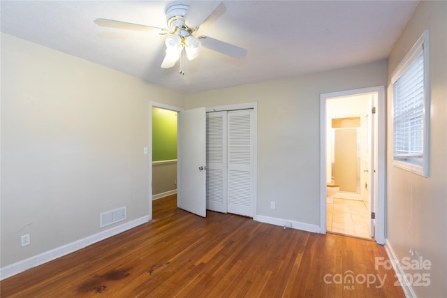 unfurnished bedroom featuring dark wood finished floors, a closet, visible vents, ceiling fan, and baseboards