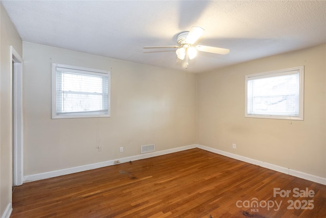 empty room featuring baseboards, visible vents, and dark wood-style flooring